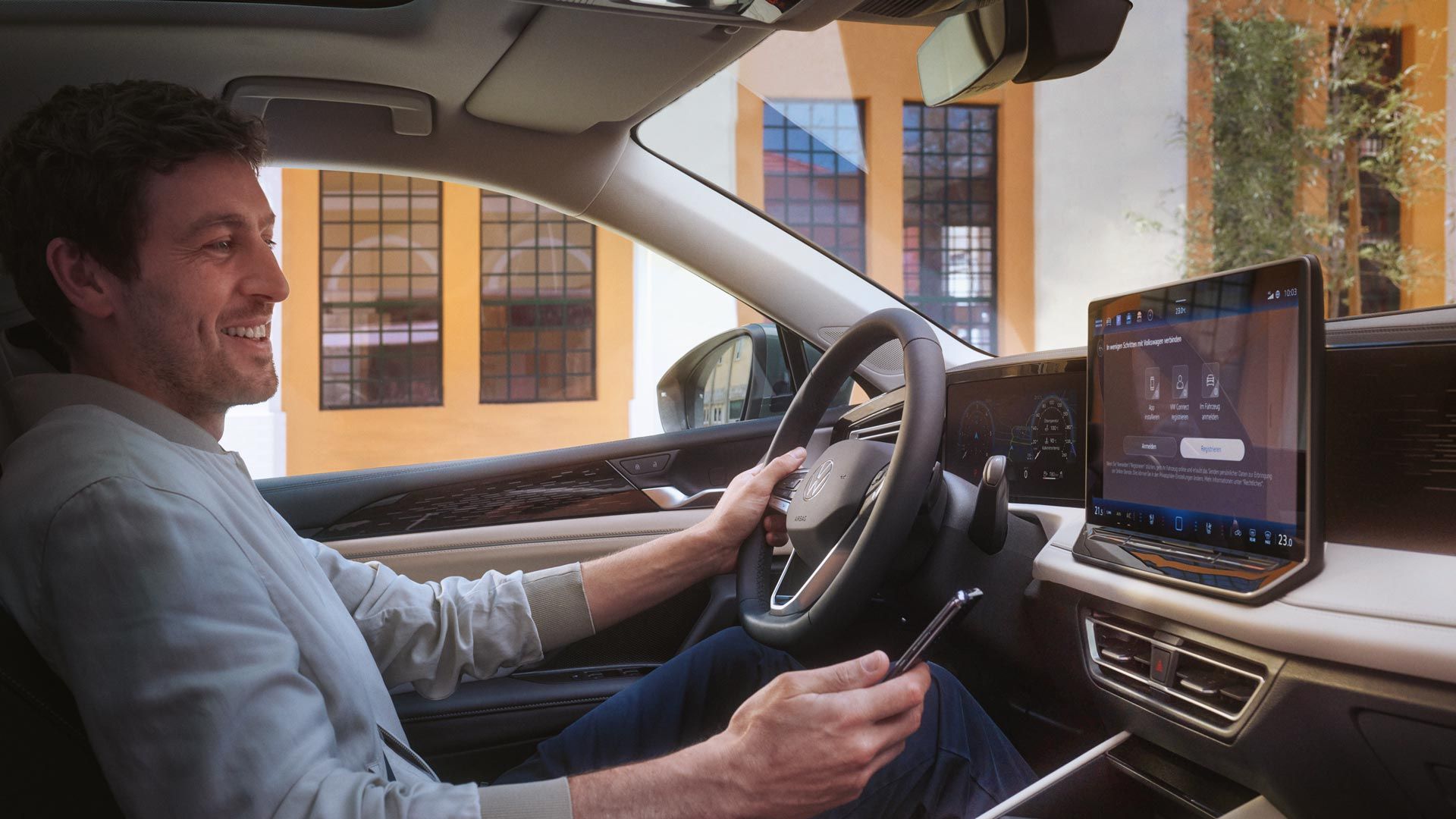 Mann sitzt in VW Tiguan und hält Smartphone in der Hand