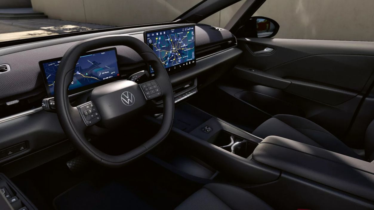 Modernes, dunkles Autointerieur mit digitalem Cockpit und großem zentralen Touchscreen, auf dem eine Navigationskarte zu sehen ist. Das Multifunktionslenkrad mit Markenlogo ist im Vordergrund, umgeben von schlanken Lüftungsdüsen und einer reduzierten Armaturenbrettgestaltung. Mittelkonsole mit Getränkehaltern und Schaltfläche, insgesamt ein aufgeräumtes, hochwertiges Design.