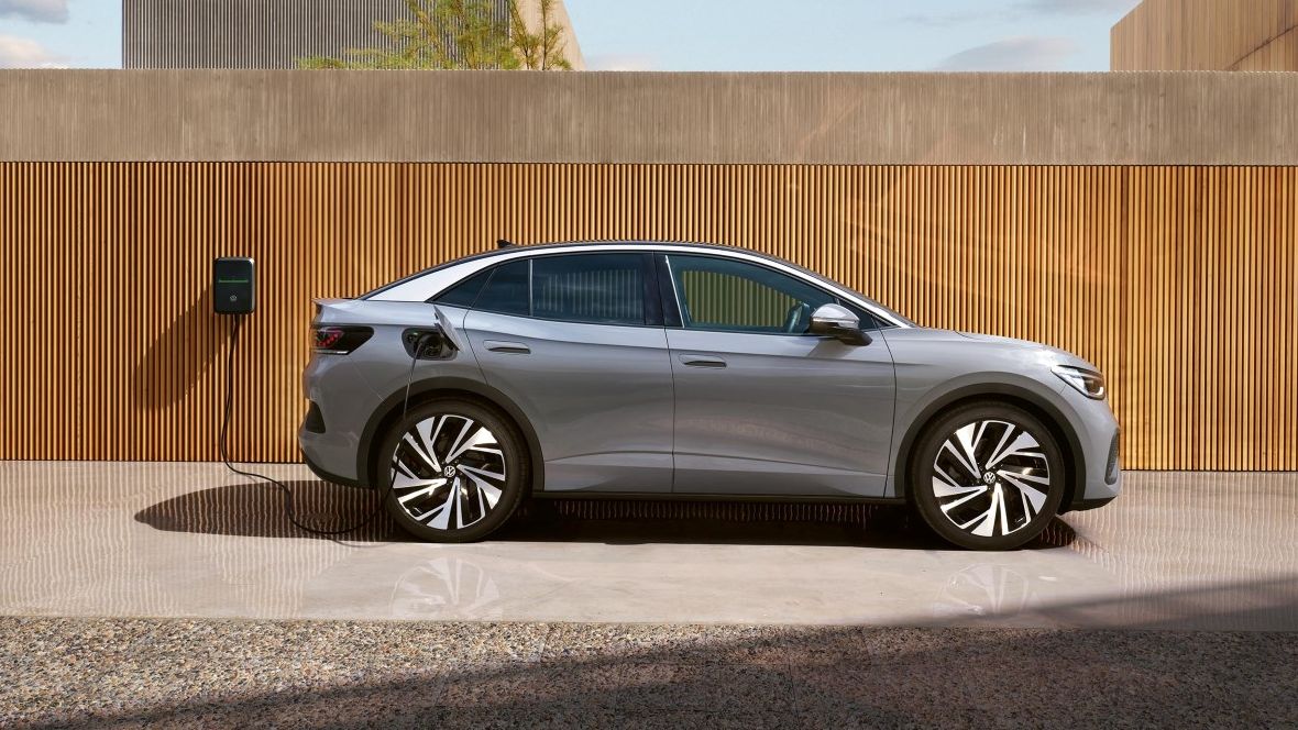 Ein grauer VW ID.5 steht seitlich vor einer Holzfassade und lädt an einer Wallbox.