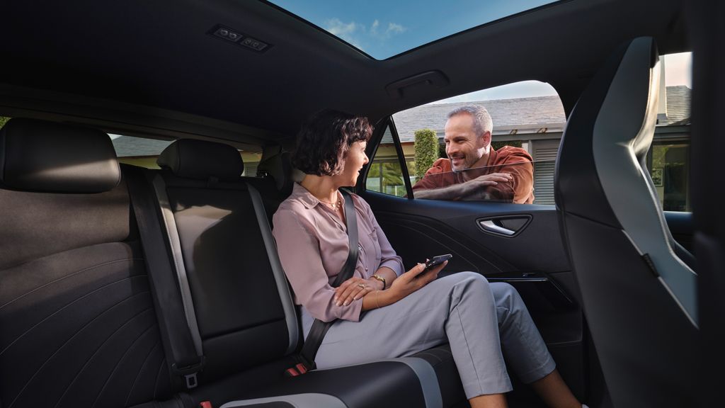 Eine Frau sitzt auf der Rückbank des VW ID.3 und redet mit einem Mann