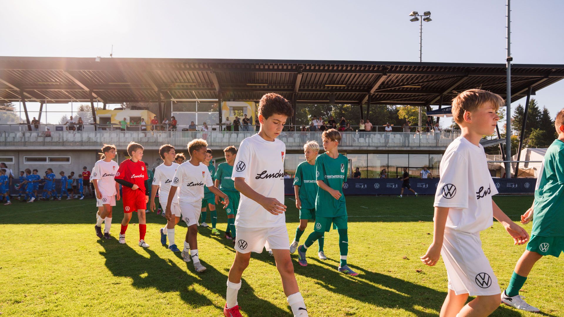 Zwei Fußballteams beim VW Junior Masters Regionalturnier gehen nebeneinander aufs Spielfeld.
